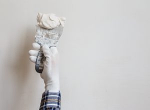 Worker in white gloves performs plastering of the walls of the room